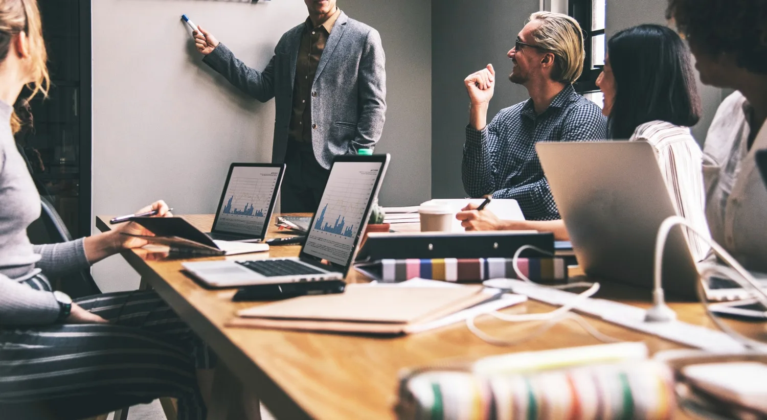 Dirigeant de petite entreprise échangeant avec un prestataire sur ordinateur, avec documents de suivi et tableau de tâches