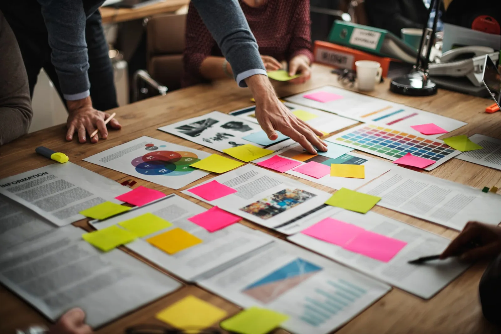 Un entrepreneur consulte ses campagnes publicitaires sur un ordinateur portable, avec smartphone, carnet de notes et supports de communication sur la table.