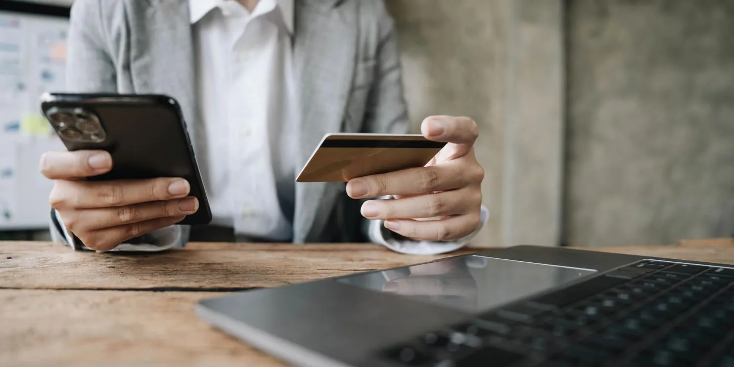 Ordinateur portable affichant une page de paiement en ligne avec carte bancaire et mobile posés à côté