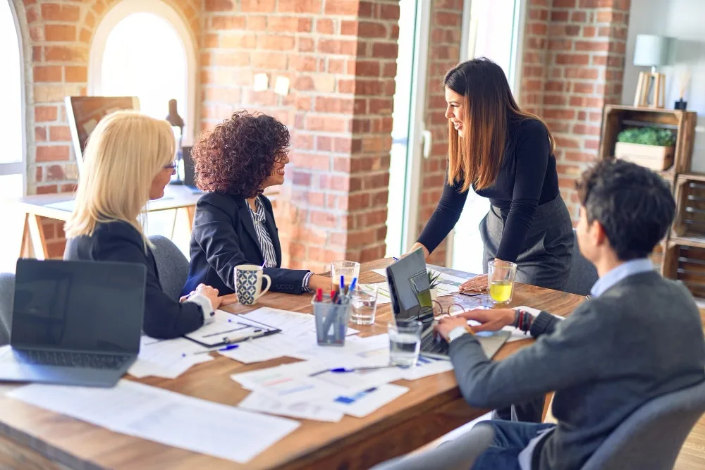 Une entrepreneuse et un entrepreneur examinent un plan d’affaires sur ordinateur portable dans un bureau lumineux