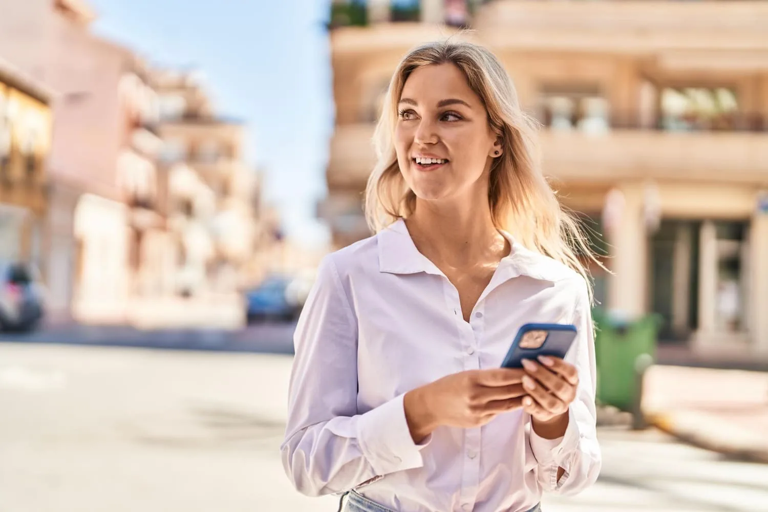 Entrepreneur consultant une plateforme d’envoi de SMS marketing sur ordinateur avec un smartphone posé à côté.