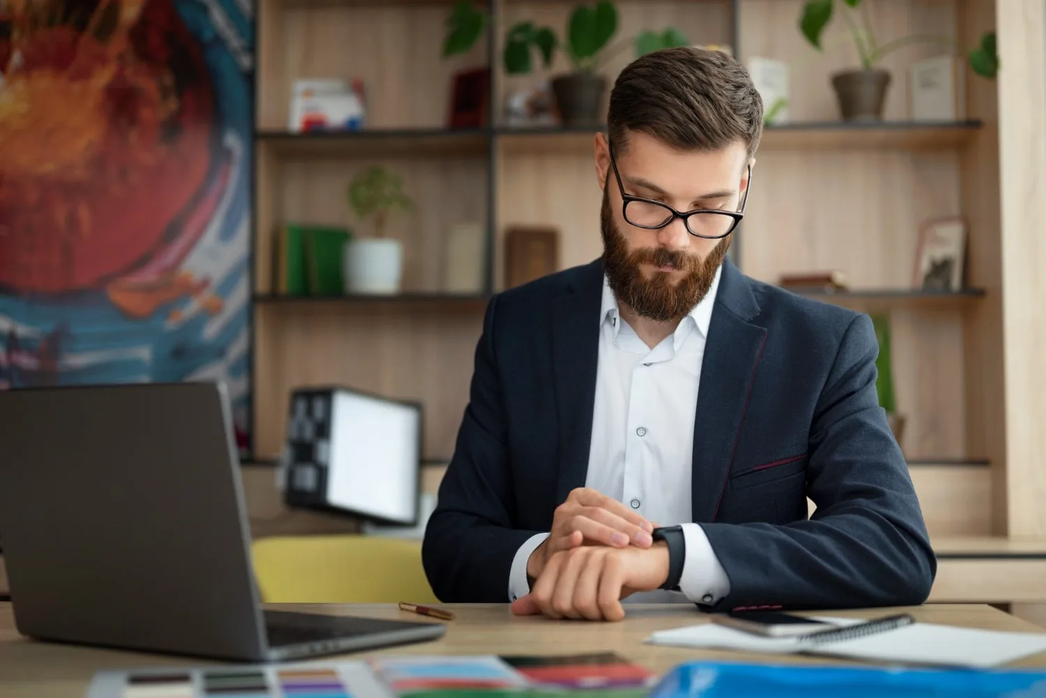 Entrepreneur travaillant sur un ordinateur portable avec un agenda ouvert et un téléphone posé à côté, dans un bureau calme
