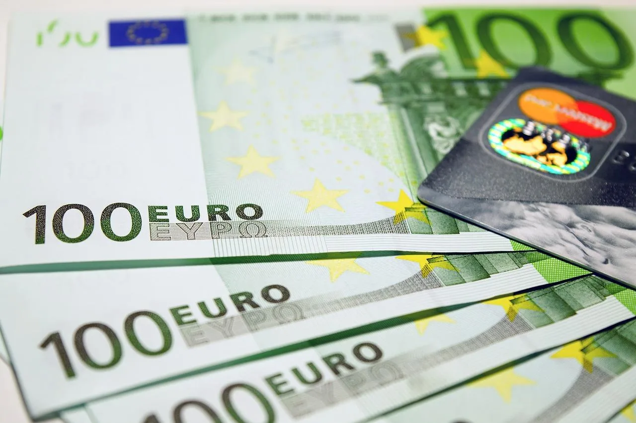 Entrepreneur individuel consultant en bureau, analysant sa trésorerie sur un ordinateur portable avec des relevés bancaires et un carnet de notes.
