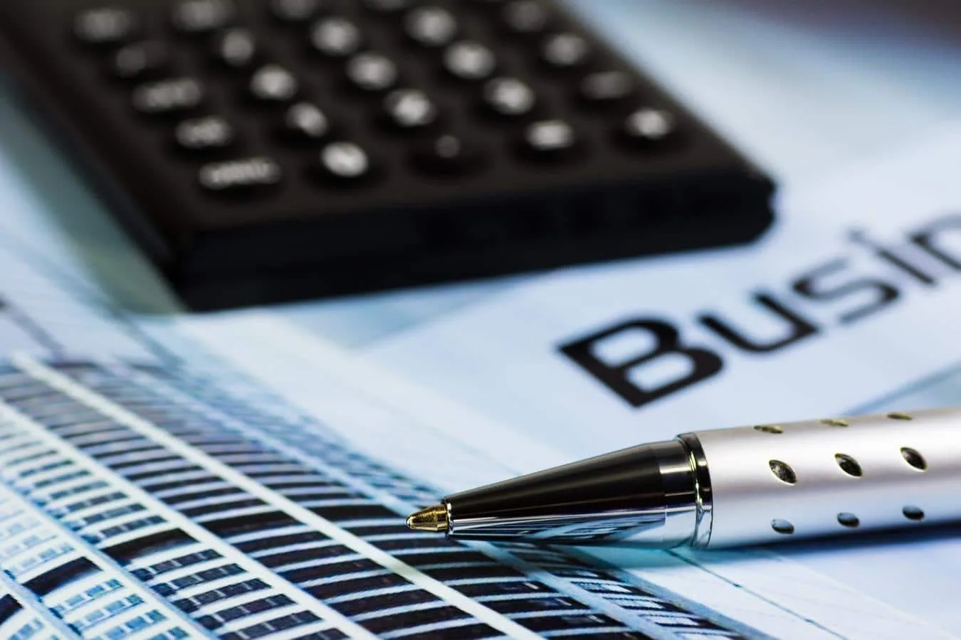 Entrepreneur individuel consultant ses factures et ses comptes sur ordinateur, avec calculatrice et documents fiscaux sur la table
