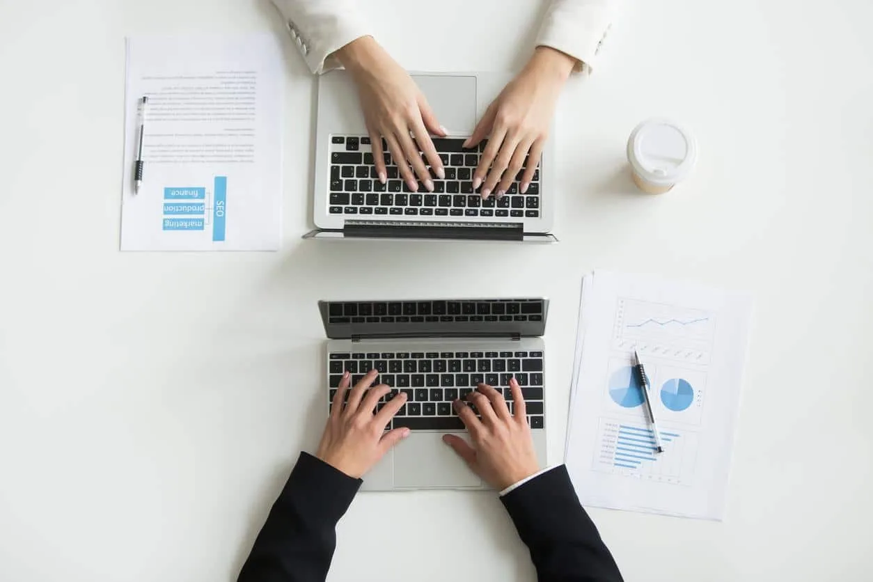 Deux personnes discutent autour de documents comptables et d’une calculatrice, dans un bureau d’entrepreneur individuel.