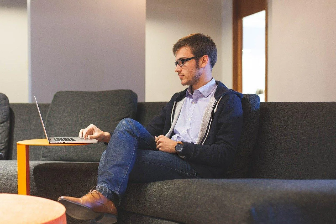 Entrepreneur individuel travaillant sur un ordinateur dans un atelier lumineux, avec des outils et des documents de gestion sur la table
