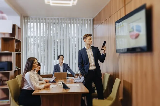 Un entrepreneur consulte le guide des programmes TV Orange sur un écran dans un espace de travail professionnel