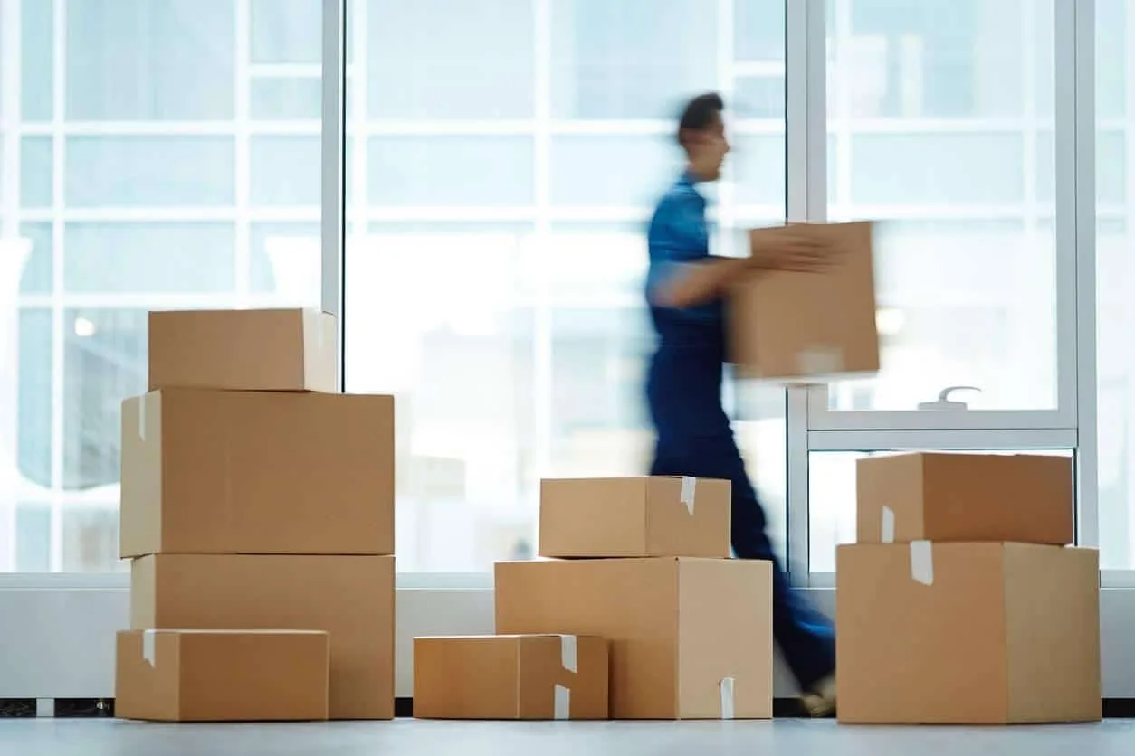Des déménageurs chargent des cartons et du mobilier de bureau devant un immeuble de bureaux
