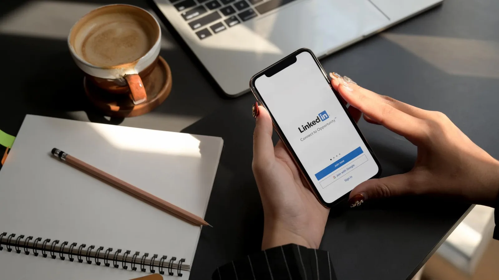 Chef d’entreprise consultant son profil LinkedIn sur ordinateur portable, avec une page entreprise affichée à l’écran