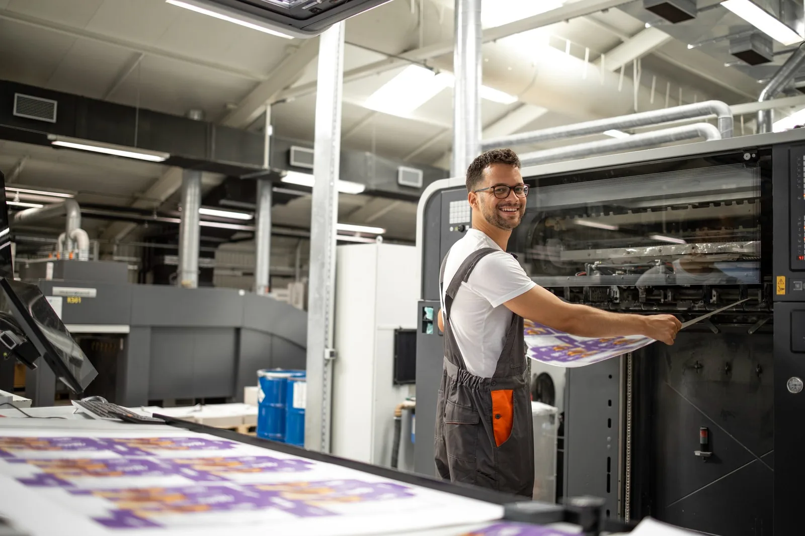Atelier d’imprimerie avec machine numérique, piles de papier et poste de façonnage