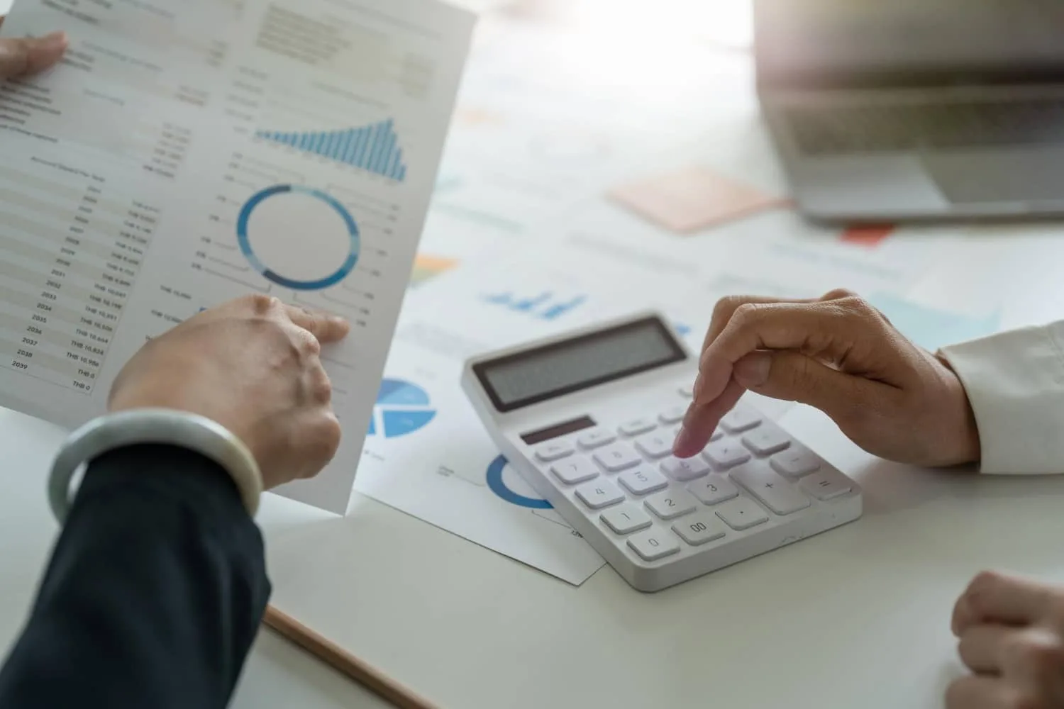 Un entrepreneur échange son business plan avec un expert-comptable autour d’un ordinateur et de documents financiers