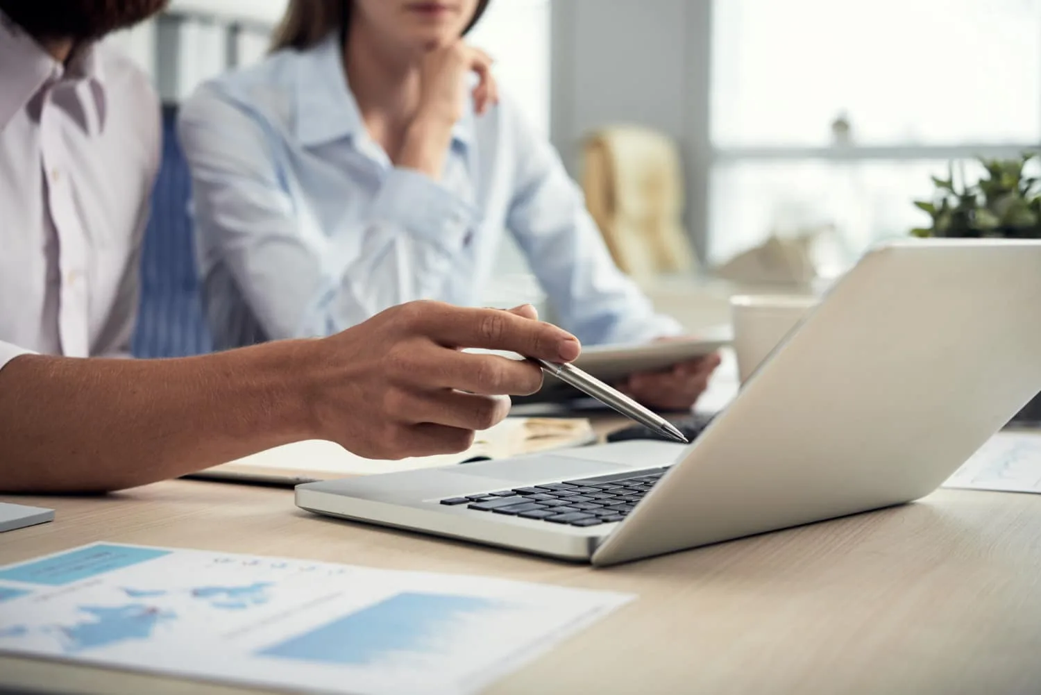 Un entrepreneur indépendant échange avec une candidate assistante autour d’un ordinateur portable et de documents de travail