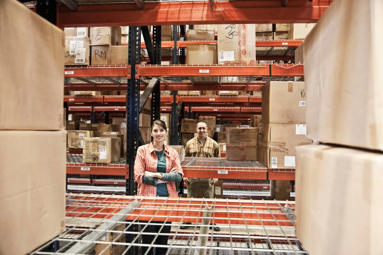 Entrepreneur préparant des fiches produits sur ordinateur avec cartons d’expédition et téléphone affichant une marketplace