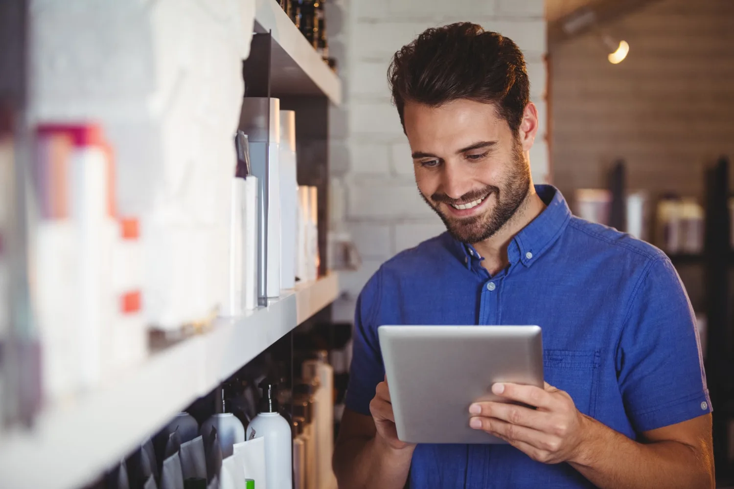 Professionnel de l’esthétique comparant des produits de beauté sur ordinateur portable avec des cartons de livraison à côté