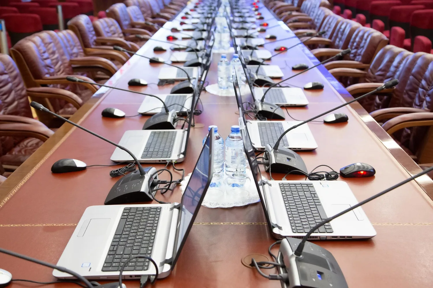 Salle de réunion moderne avec microphone de conférence, enceintes murales et ordinateur portable sur la table